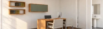 Visualización del interior de una oficina modular con escritorio, dos sillas de visita, estanterías y zona de aseo.