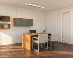 Visualización del interior de una oficina modular con escritorio, dos sillas de visita, estanterías y zona de aseo.